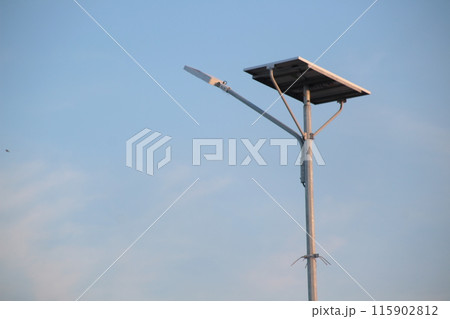 a solar-powered street light with a clear blue sky background. 115902812