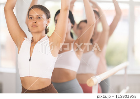 Young girl practicing fifth arm position holding by ballet barre Young girl practicing fifth arm position holding by ballet barre 115902958