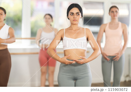 Girls in sportswear rehearsing ballet poses in choreographic studio Girls in sportswear rehearsing ballet poses in choreographic studio 115903072