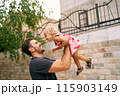 Smiling dad lifts a high laughing little girl. Portrait. High quality photo 115903149
