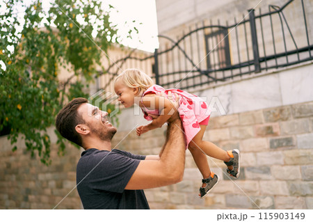 Smiling dad lifts a high laughing little girl. Portrait. High quality photo Smiling dad lifts a high laughing little girl. Portrait. High quality photo 115903149