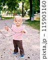 Little girl with a stick in her hands stands in the park. High quality photo 115903160