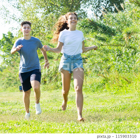 Cheerful teenagers are jogging together in park and having fun 115903310