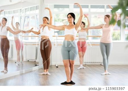 Young girl practicing ballet positions standing in row with others Young girl practicing ballet positions standing in row with others 115903397