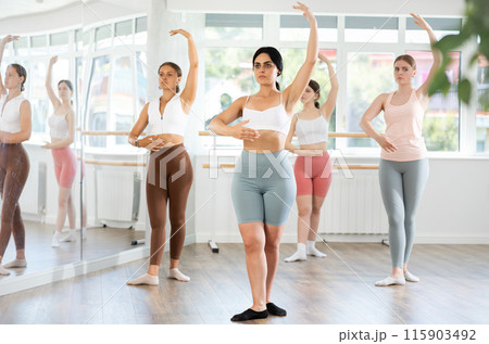 Young girl practicing ballet positions standing in row with others Young girl practicing ballet positions standing in row with others 115903492