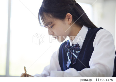 学校の教室で授業を受ける女子高生 115904370
