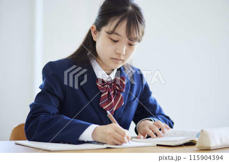 学校の教室で授業を受ける女子高生 115904394