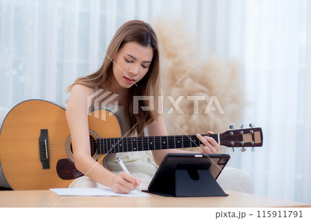 Young asian woman sitting on sofa looking tablet and compose a song for practice music. Young asian woman sitting on sofa looking tablet and compose a song for practice music. 115911791