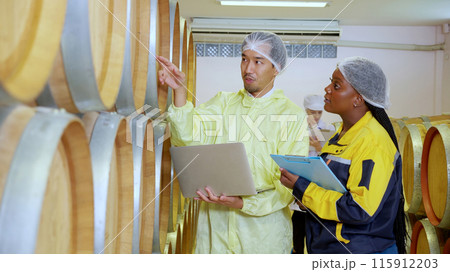 Winemaker team checking and examining producing wine at winery in factory. Winemaker team checking and examining producing wine at winery in factory. 115912203
