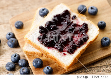 Blueberry jam with fresh berries on bread on rustic wooden table background. Selective focus. 115914642
