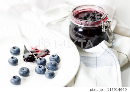Blueberry jam with fresh berries on white marble table background. Selective focus. Blueberry jam with fresh berries on white marble table background. Selective focus. 115914669