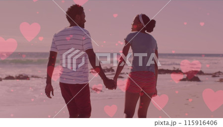 Multiple pink hearts floating against african american couple holding hands and walking on the beach Multiple pink hearts floating against african american couple holding hands and walking on the beach 115916406