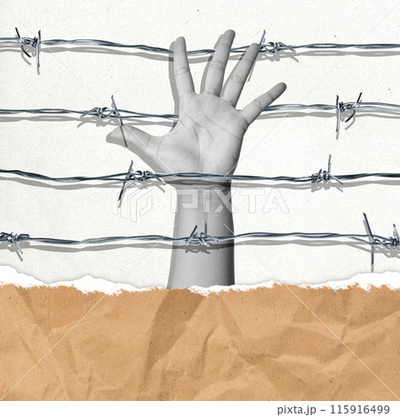 A human hand raised in the air in the middle of barbed wire 115916499