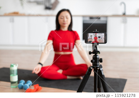 Woman meditating at home recording video with smartphone Woman meditating at home recording video with smartphone 115921278