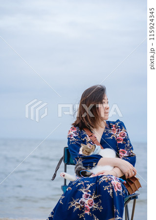 woman relax sit on beach chair and hug her cat on sand beach 115924345