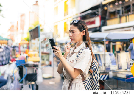 Young Asian woman getting lost and using map on a mobile phone while traveling and backpacker in Khaosan Road outdoor market in Bangkok, Thailand Young Asian woman getting lost and using map on a mobile phone while traveling and backpacker in Khaosan Road outdoor market in Bangkok, Thailand 115925281