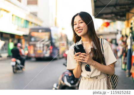 Smiling Asian woman traveller backpacker using application of taxi service app on smart phone Smiling Asian woman traveller backpacker using application of taxi service app on smart phone 115925282
