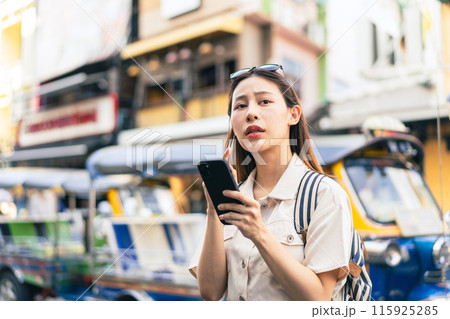 Young Asian woman getting lost and using map on a mobile phone while traveling and backpacker in Khaosan Road outdoor market in Bangkok, Thailand 115925285