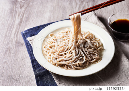 十割蕎麦、木のテーブルの上に、お皿に盛ったざるそばを箸で蕎麦を持ち上げる。クラッシックなイメージ 115925384