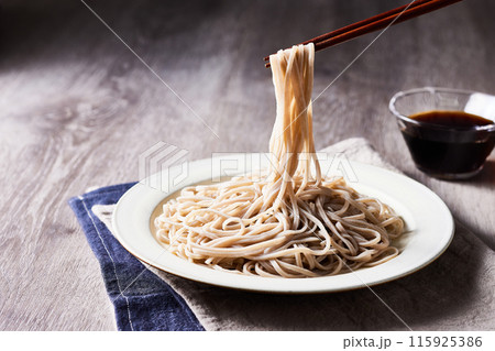 十割蕎麦、木のテーブルの上に、お皿に盛ったざるそばを箸で蕎麦を持ち上げる。クラッシックなイメージ 115925386