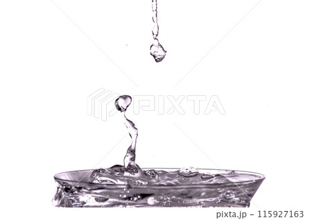 Close-up of water drop falling into a glass on white background 115927163