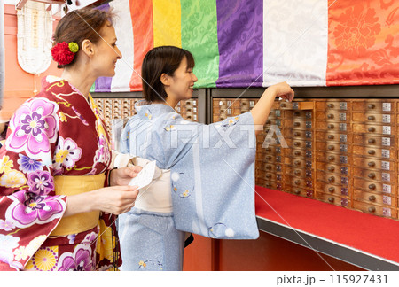 おみくじをする着物姿の外国人女性と案内する日本人女性 おみくじをする着物姿の外国人女性と案内する日本人女性 115927431