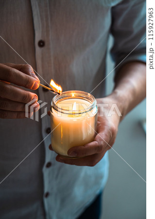 Man holding a burning candle in his hands, elegant young man with candle jar, meditation and mindfulness concept Man holding a burning candle in his hands, elegant young man with candle jar, meditation and mindfulness concept 115927963