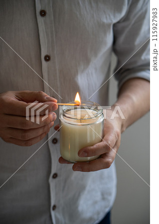 Man holding a burning candle in his hands, elegant young man with candle jar, meditation and mindfulness concept 115927983