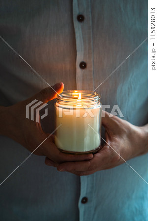 Man holding a burning candle in his hands, elegant young man with candle jar, meditation and mindfulness concept Man holding a burning candle in his hands, elegant young man with candle jar, meditation and mindfulness concept 115928013