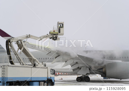 De-icing the aircraft before the flight. The deicing machine sprinkles the wing of a passenger plane with antifreeze. Winter at the airport. Snow. Aviation handling. Steam. Airport service 115928095