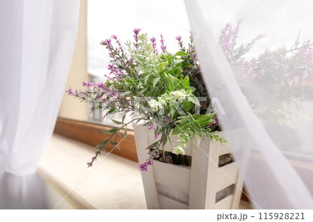 Artificial plant purple flower on window sill Artificial plant purple flower on window sill 115928221