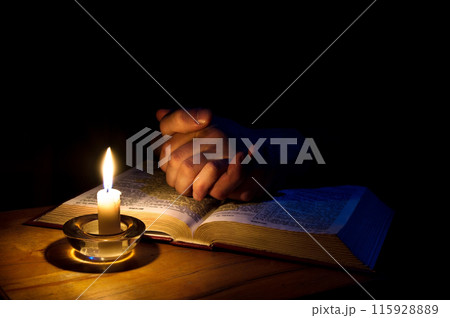 Hands folded in prayer over Scriptures 115928889