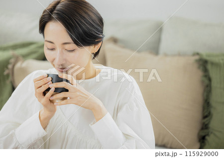 リビングでコーヒーを飲むミドル女性 115929000