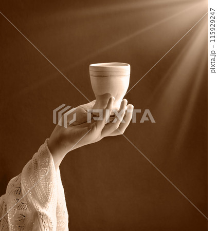 A hand in ancient clothing holds a clay bowl 115929247