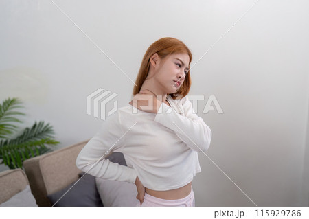 Woman Experiencing Neck and Back Pain at Home, Demonstrating Discomfort and Ache in a Modern Living Space 115929786
