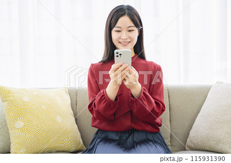 リビングでスマホを見る女性 115931390
