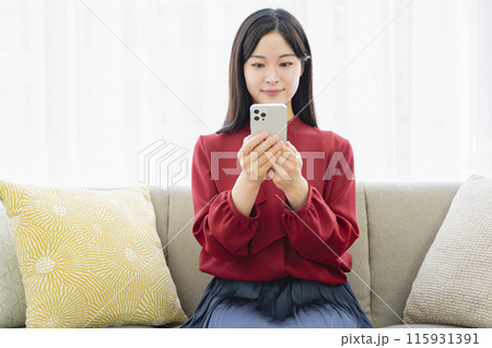 リビングでスマホを見る女性 115931391