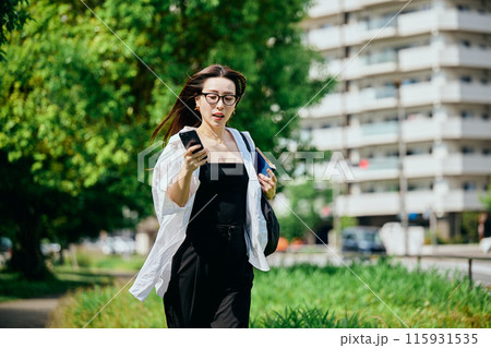 スマホを持って街を走る若い女性 スマホを持って街を走る若い女性 115931535