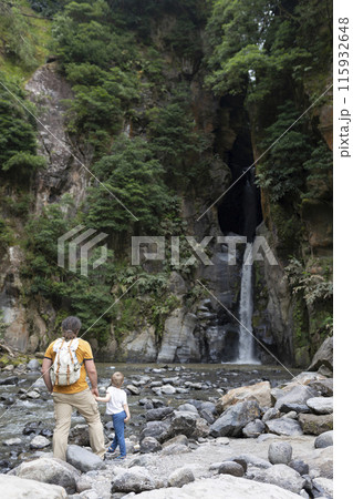 A man and a child are standing near a waterfall A man and a child are standing near a waterfall 115932648