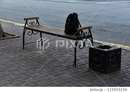 A black wooden bench in the city in the evening. A place to relax in the park. A black wooden bench in the city in the evening. A place to relax in the park. 115933239