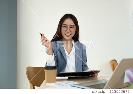 Young Professional Woman Working at Desk with Tablet and Coffee in Modern Office Environment Young Professional Woman Working at Desk with Tablet and Coffee in Modern Office Environment 115933672