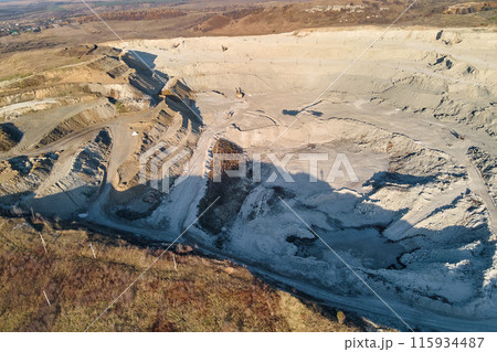 Aerial view of open pit mine of sandstone materials for construction industry with excavators and dump trucks. Heavy equipment in mining and production of useful minerals concept Aerial view of open pit mine of sandstone materials for construction industry with excavators and dump trucks. Heavy equipment in mining and production of useful minerals concept 115934487