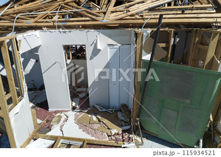 Wind destroyed house roof and walls with missing asphalt shingles after hurricane Ian in Florida. Demolition of building after natural disaster Wind destroyed house roof and walls with missing asphalt shingles after hurricane Ian in Florida. Demolition of building after natural disaster 115934521