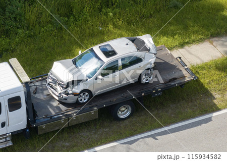 Tow truck loading crashed car on accident site. Emergency services personnel and vehicles responding to vehicle crash on American street. First responders helping on road in the USA Tow truck loading crashed car on accident site. Emergency services personnel and vehicles responding to vehicle crash on American street. First responders helping on road in the USA 115934582