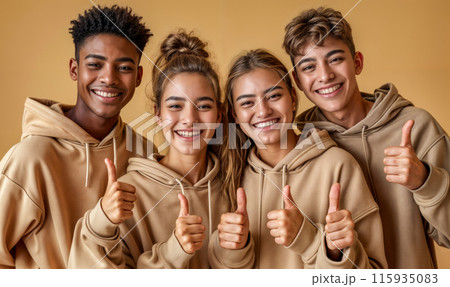Four young people are smiling and giving thumbs up to the camera 115935083