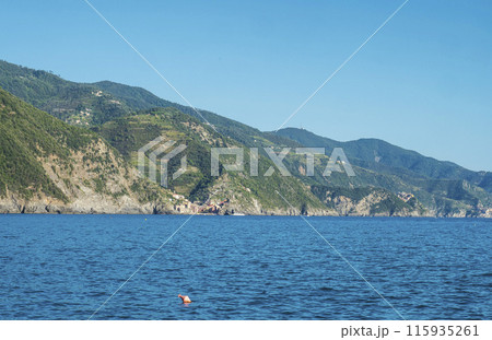 Coastline view from distance of the area Cinque Terre coast with Vernazza and Corniglia Villages of National Park with ligurian sea and blue sky. La Spezia, Liguria, Beautiful mountain. Copy space Coastline view from distance of the area Cinque Terre coast with Vernazza and Corniglia Villages of National Park with ligurian sea and blue sky. La Spezia, Liguria, Beautiful mountain. Copy space 115935261