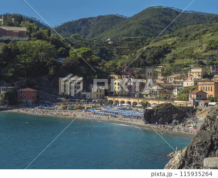 Picturesque view of Monterosso al Mare with beach, colorful houses, train rails, bell tower and Torre Bastioni with green cliffs, clear blue sky and sea. National park Cinque Terre, Liguria, Italy 115935264