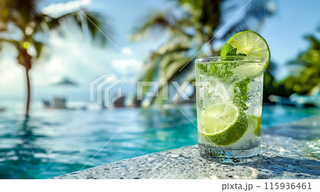 Refreshing mojito by the pool, a cocktail decorated with lime and mint against the backdrop of crystal clear water in the pool and palm trees, an idyllic summer scene 115936461