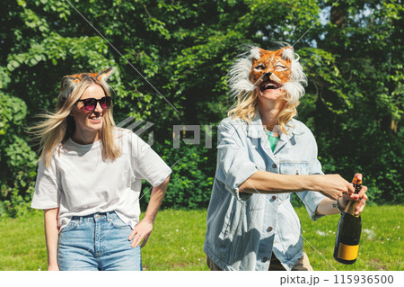 Two young adult beautiful woman girls friends enjoy have fun wearing animal mask laughing at picnic party city park green garden at sunny day. Female person friendship summer outdoors celebration 115936500
