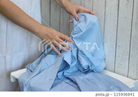 The woman makes a review of the summer dress of blue. Lays it on the table. 115936841